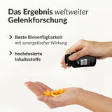 Hand holding multiple yellow capsules poured from black 5er Rock Solid bottle with joint research text background