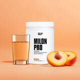 Milon Pro Dose mit Pfirsichgeschmack, Glas mit Getränk und halbierter Pfirsich vor orangefarbenem Hintergrund, Galerie 1