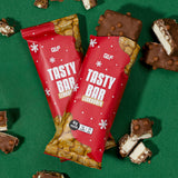 Tasty Bar Proteinriegel Lebkuchen mit 16g Protein, umgeben von aufgeschnittenen Riegelstücken auf grünem Untergrund, Galerieposition 1