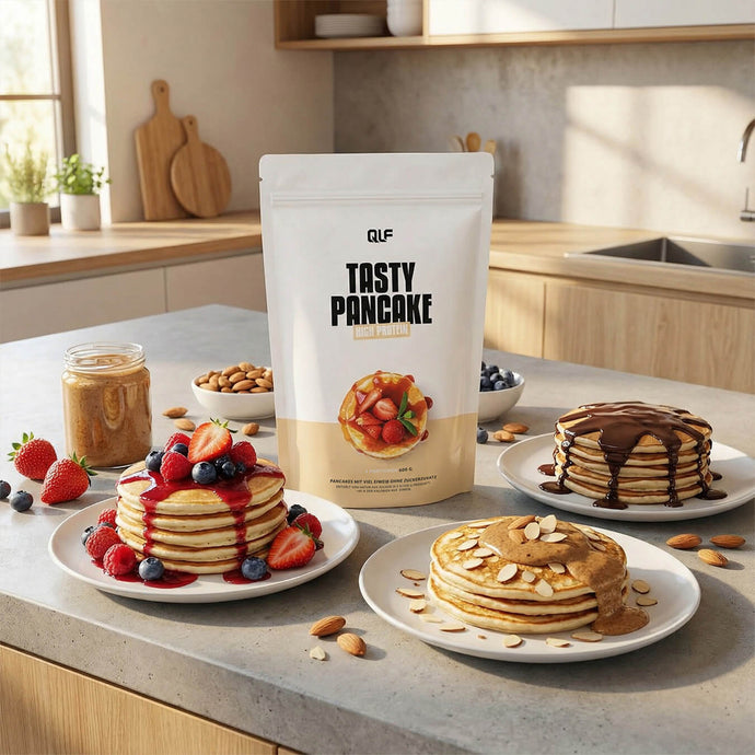 Three plates of pancakes with different toppings including berries, almonds, and chocolate sauce beside a Tasty Pancake mix pouch on countertop