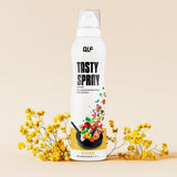 Tasty Spray Kaloriensparendes Kochspray in weißer Flasche mit Gemüsespritzern, dekoriert mit gelben Blumen, Galerieposition 1
