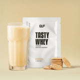 Tasty Whey Proteinpulver Butterkeks Sachet mit cremigem Shake im Glas und Butterkeksen vor hellem Hintergrund Galerie 1