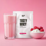Tasty Whey Proteinpulver Himbeer Joghurt mit Shake im Glas, Schale Sahne und frischen Himbeeren vor rosa Hintergrund