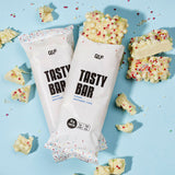 Tasty Bar Proteinriegel Birthday Cake mit 15g Protein, weißer Schokolade und bunten Streuseln auf hellblauem Hintergrund, Galerieposition 1