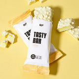 Tasty Bar Proteinriegel Eierlikör-Variante mit weißer Schokolade und knackiger Textur vor gelbem Hintergrund, Galerie 1