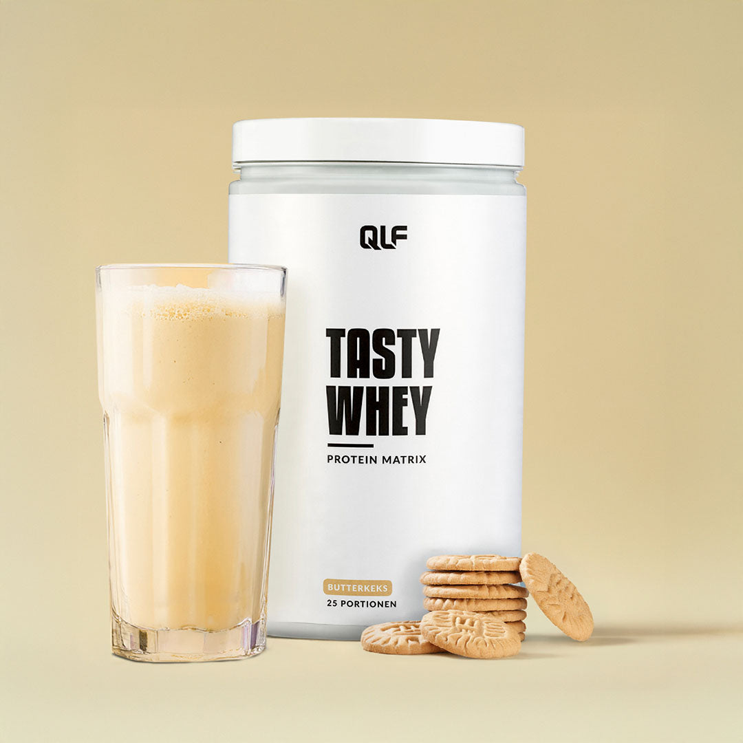 Tasty Whey Proteinpulver Butterkeks Geschmack mit Shake im Glas und Keksstapel auf hellbeigem Hintergrund, Galerie 1