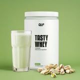 Tasty Whey Proteinpulver Pistazie mit Shake im Glas und Pistazien auf grünem Hintergrund, Galerieposition 1