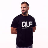 QLF Squad T-Shirt (großes Logo) in schwarz, Modell steht seitlich, klarer weißer Quantum Leap Fitness Schriftzug Galerie 1